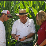 Agent keith perkins consults his GPS while talking to clients in a corn field