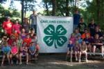 4-H youth sitting on bleachers with 4H banner at camp