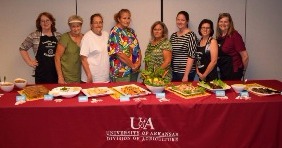 Women standing behind a table with food displayed on it