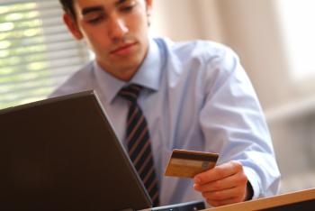 Man in front of computer looking at credit card