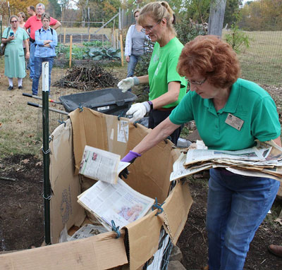  Master Gardeners toss old newspaper into the bottom of their "keyhole garden" demonstration at the St. Joseph Community Garden
