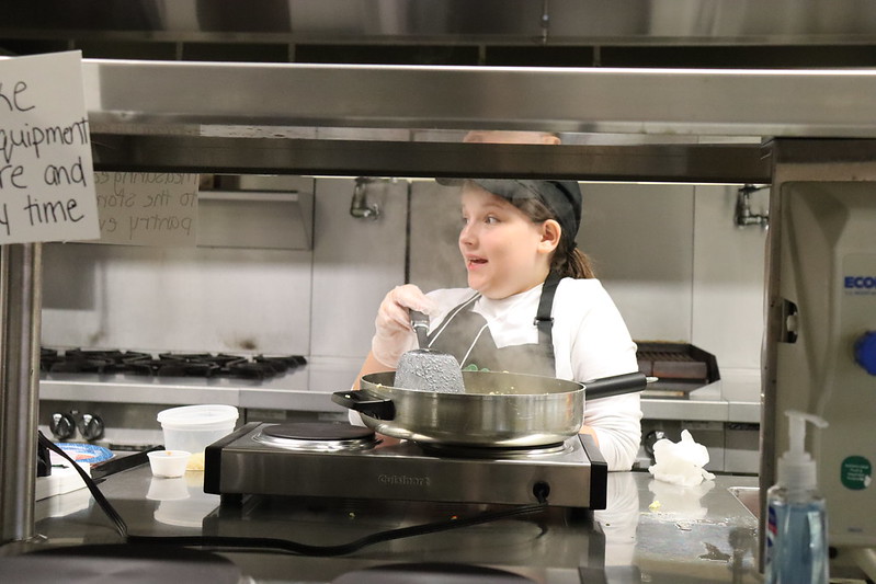 Young chef whipping up a dish in a commercial kitchen