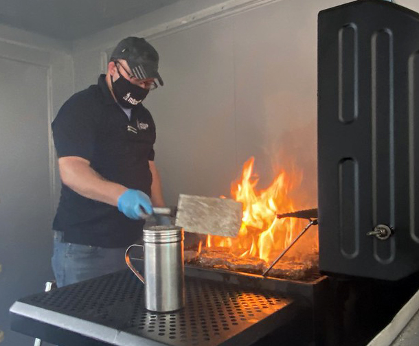 Man grilling with flames popping up.