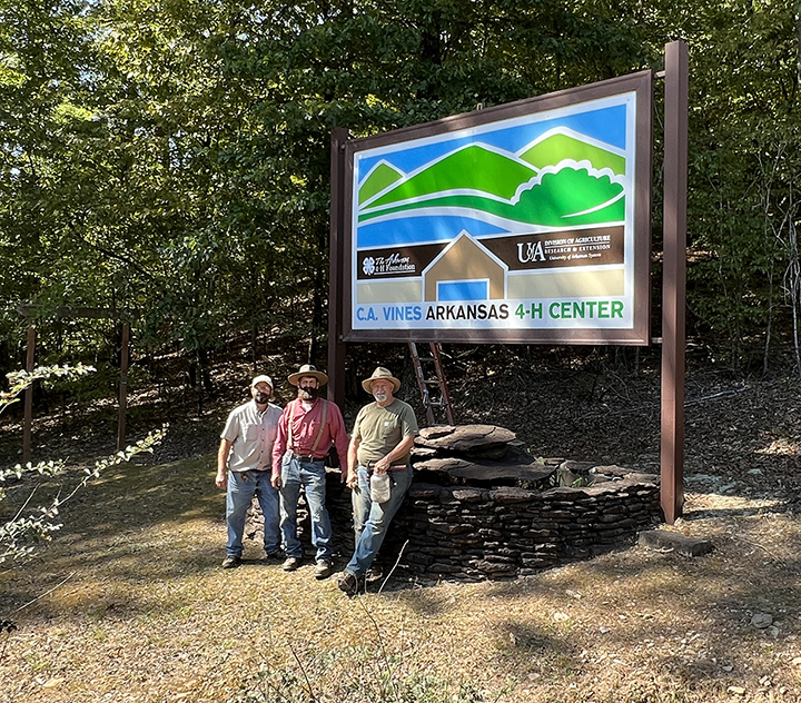 Three people standing in front of a sign