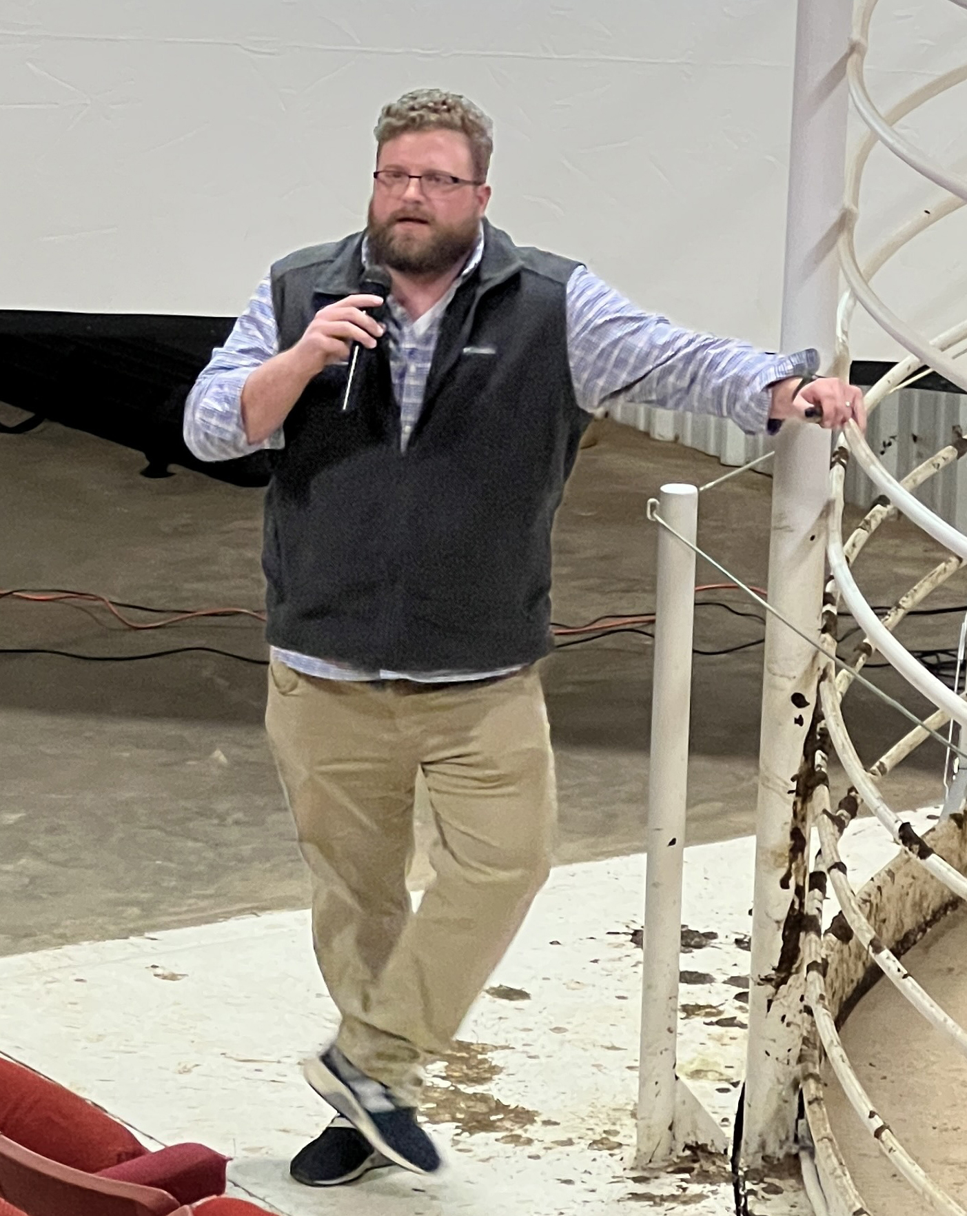 James Mitchell standing on the floor of a cattle auction speaking to audience.