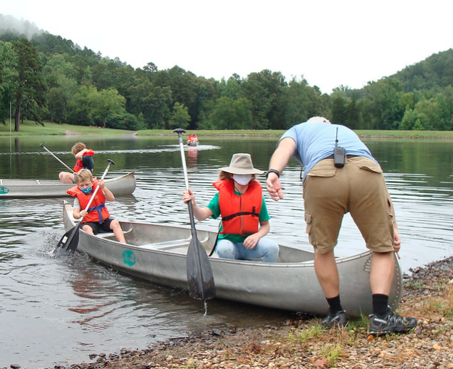 Masked campers getting canoe going.