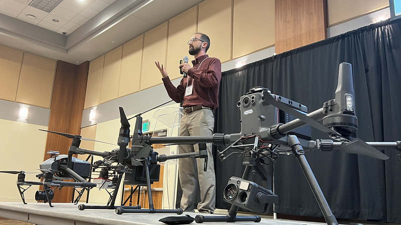 Jason Davis speaking onstage, with drones in foreground