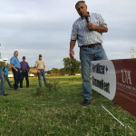 agent holding microphone talking to clients about grass