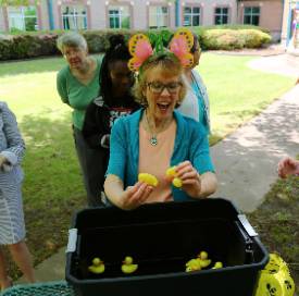 Woman choosing plastic duck out of a water bin as a random prize at an outdoor event