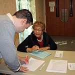 man signing a form while a woman looks on