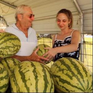 Watermelon vendor presenting watermelin to customer