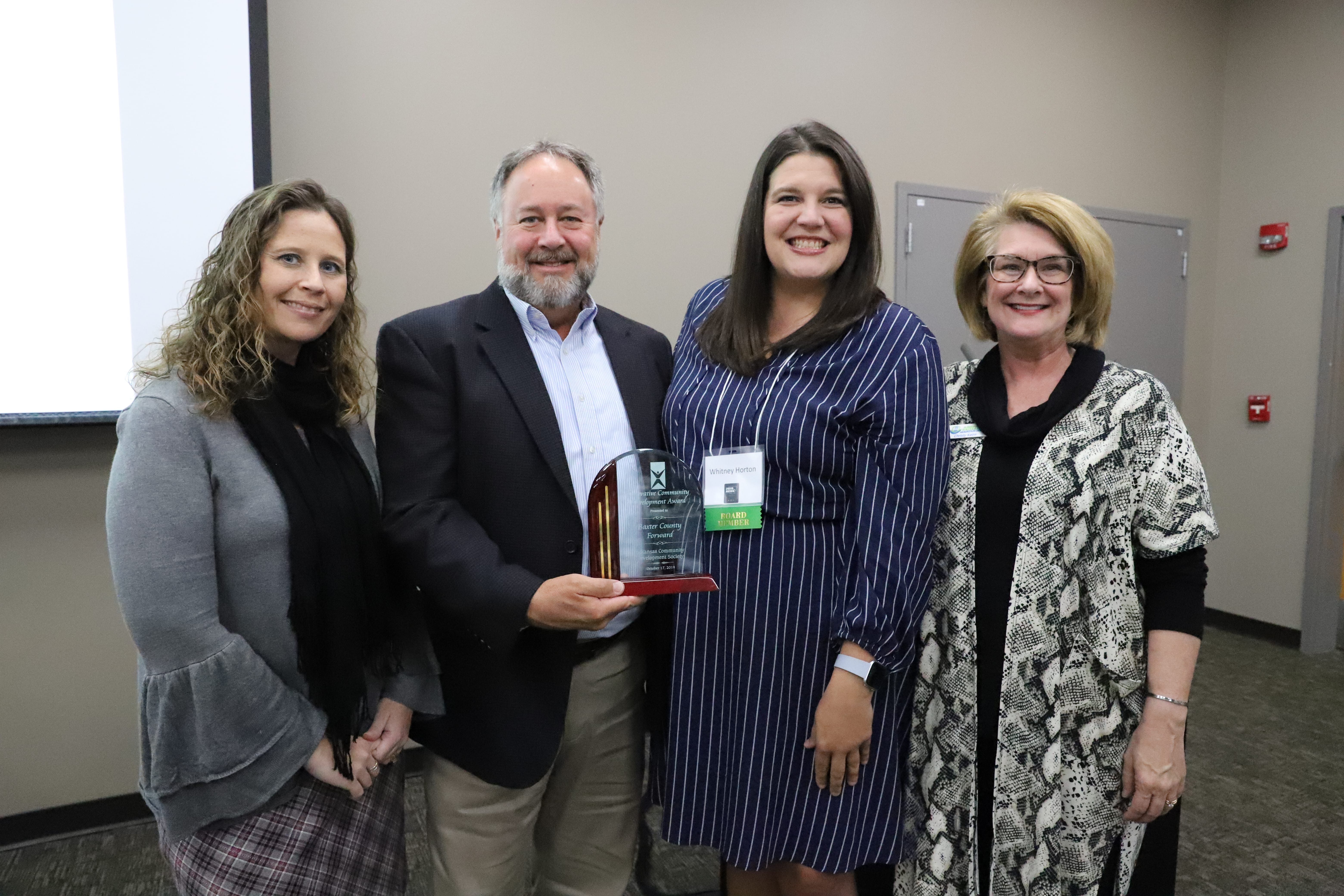 Receiving the Innovative Community Development Award for Baxter County Forward are Angela Broome, Jeff Pipkin, and Christy Keirn. Presenting the award is Whitney Horton, Vice President of the Arkansas Community Development Society (third from the left).