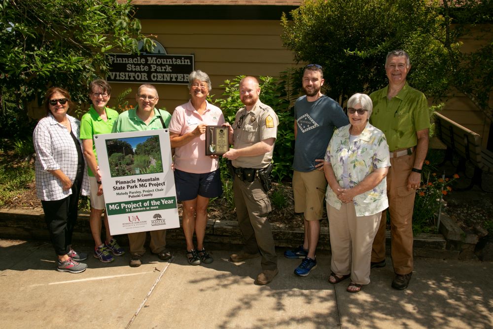 Group of people holding award in front of garden