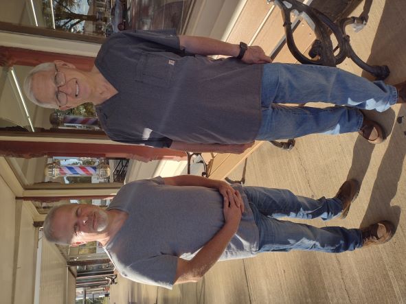 two men standing in front of a glass window in front of a business