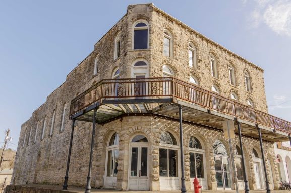 Image of corner of a building with 3 stories of cobblestone