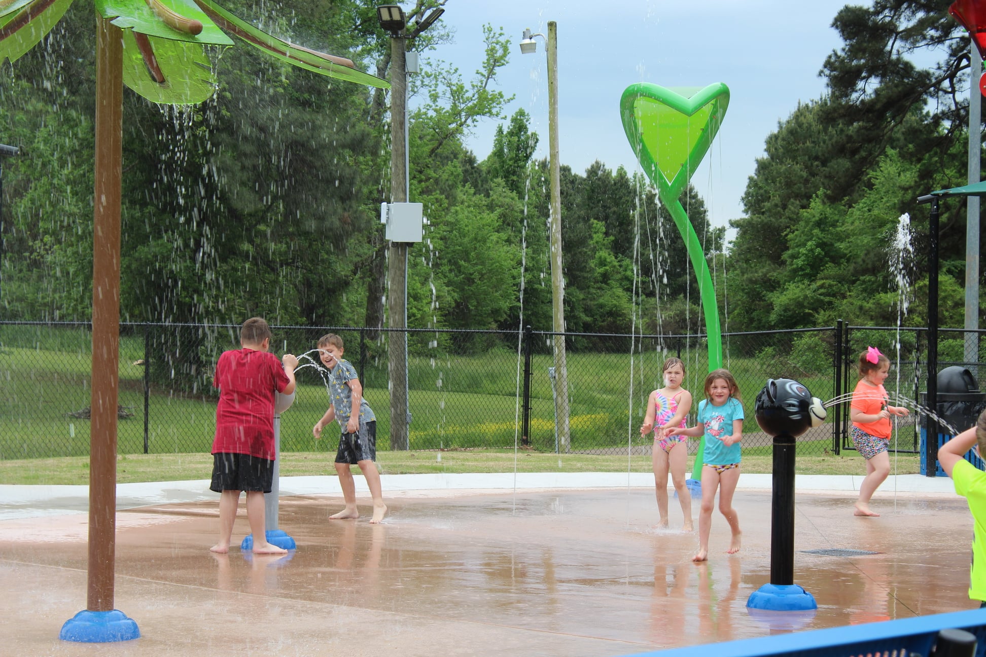 Children playing under water sprinklers