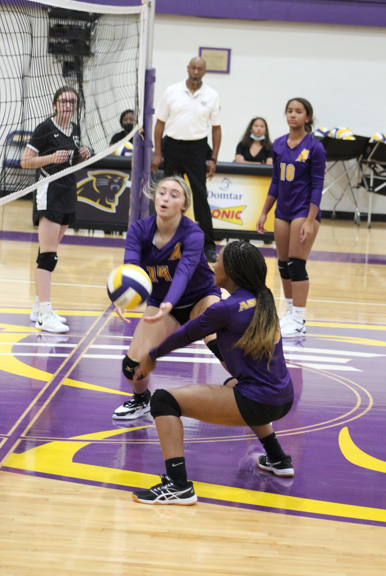 Girl looking to dig a volleyball in a volleyball game with other girls in backround