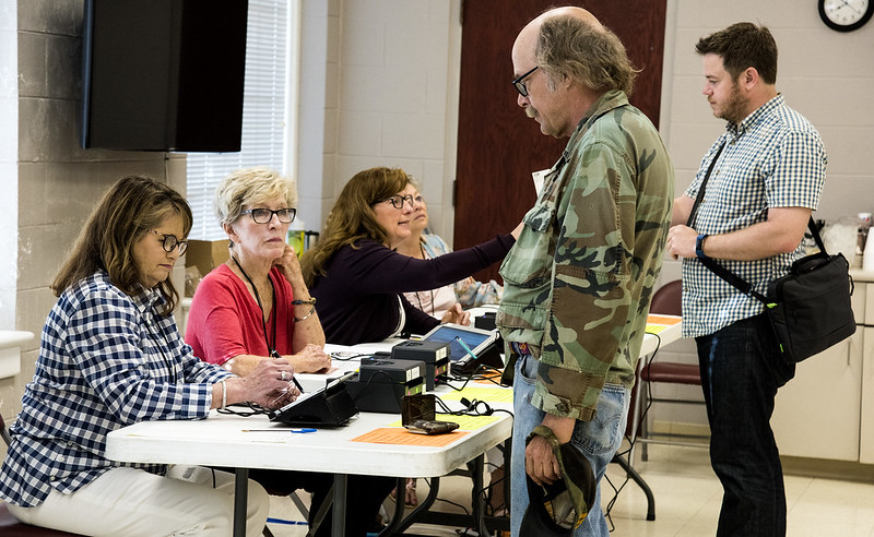 A voter presents his ID to check in at a Washington County primary election polling site in May 2018.  Division of Agriculture photo by Fred Miller