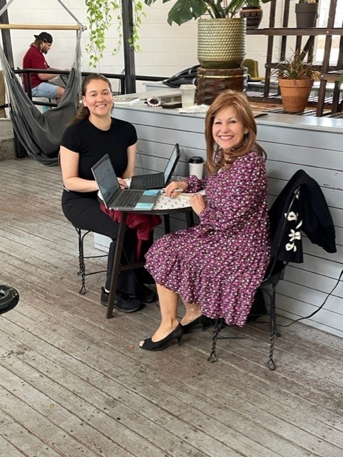 Two women sitting at a table smiling at camera