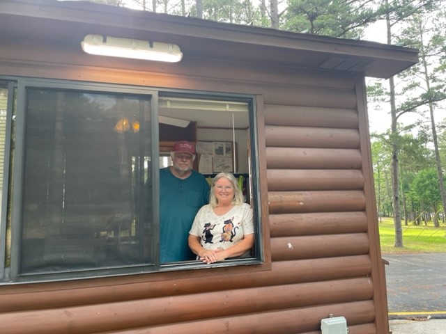 A man and woman stand behind an open window