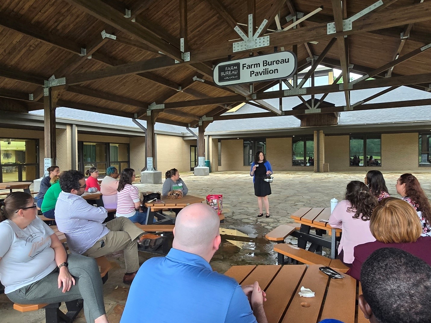 Dr. Julie Robinson stands talking to a seated LeadAR Class 21 in a pavilion