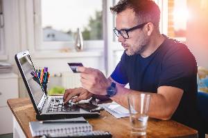 online shopping man holding a credit card and looking at a laptop to shop online
