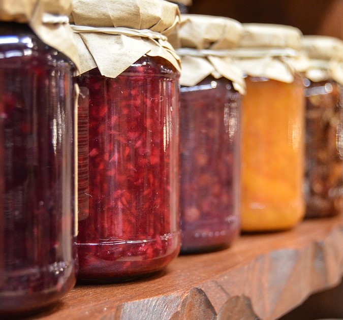 Glass jars of red, yellow, and purple jams.