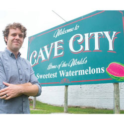 Man standing in front of Cave City sign