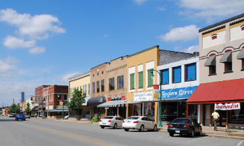 Downtown Stuttgart - older buildings on a main street with cars parked in front. Person walking on a sidewalk