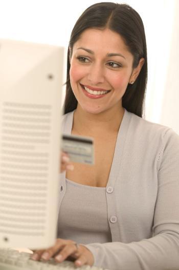 Woman sitting at computer and holding credit card