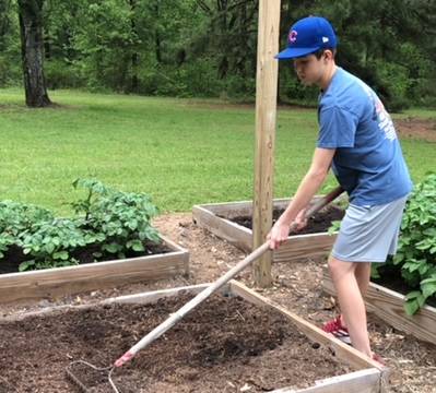 boy raking soil in a raised bed garden