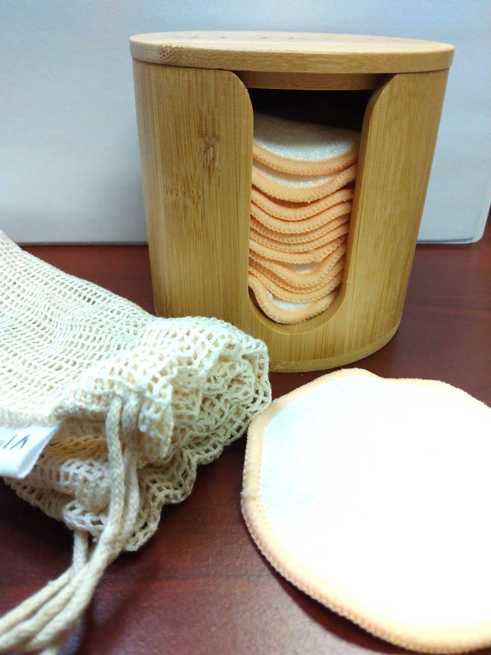 stack of cotton makeup rounds in a bamboo container on a counter