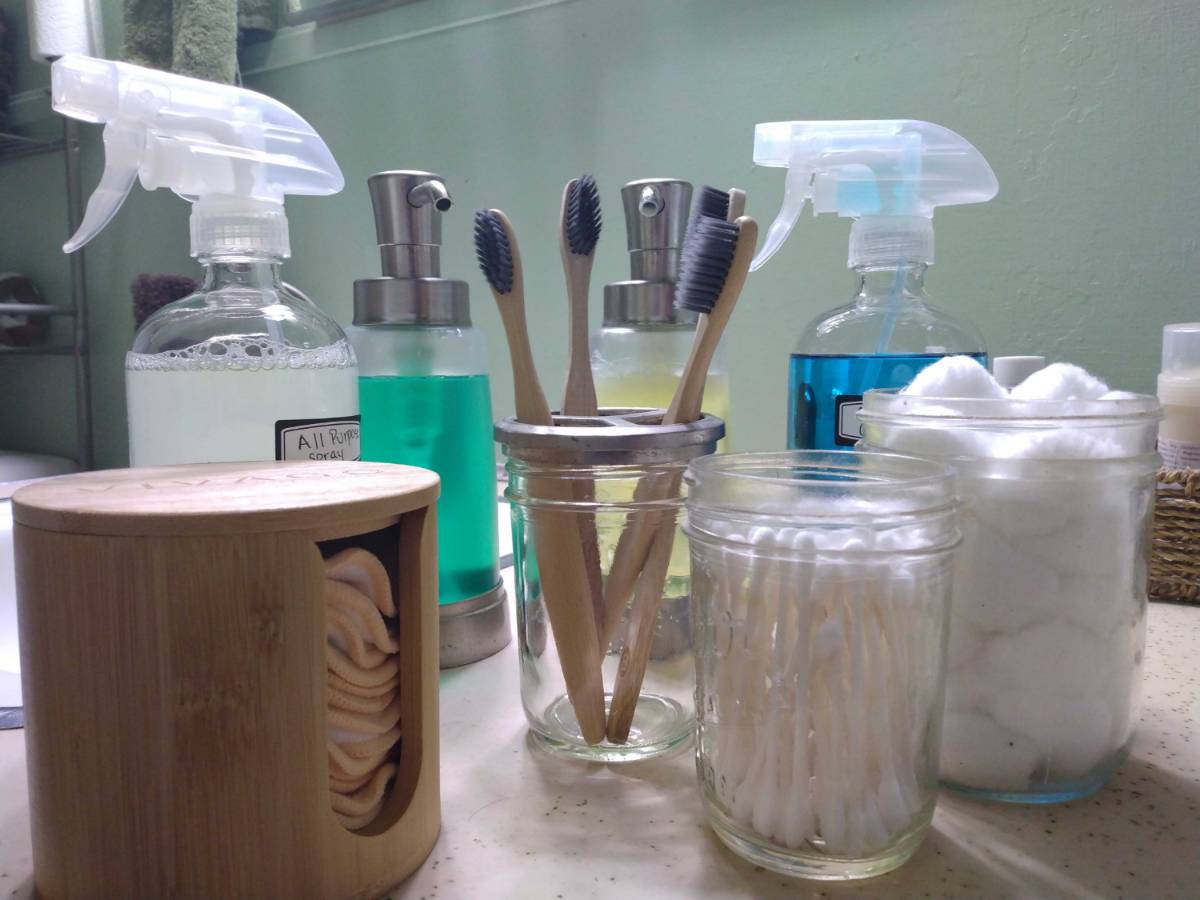 toothbrush holder and cotton swabs and cleaning pads on a counter
