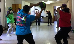 People exercising with medicine balls, lifting weighted balls while standing with knees slightly bent