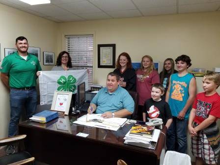 Fulton County 4-H Proclamation.  4-H members & UofA Agents standing behind the county judge as he signs the proclamation.
