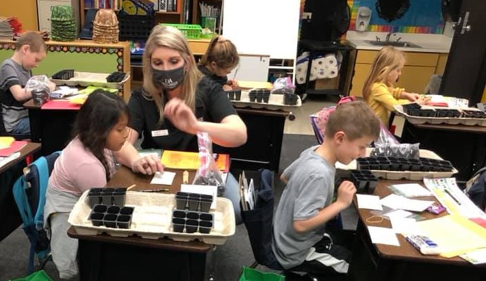  Group of children in a classroom learning how to plant seeds.