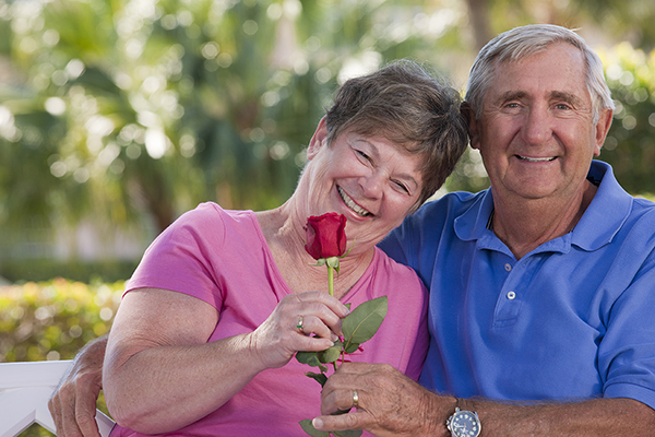 older couple smiling and holding a rose for valentine's day