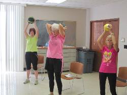 Three women training with medicine balls during a Get Fit session 