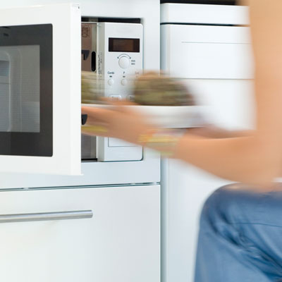 college girl putting food in microwave at a run