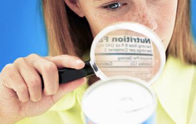 woman with magnifying glass reading nutrition label