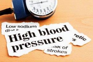 blood pressure monitor with pieces of paper with symptoms of high blood pressure written on them