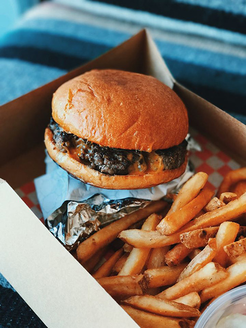 Hamburger and fries in take out container