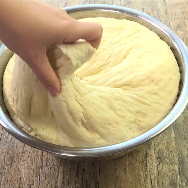 pinching off some dough from a bowl to bake bread
