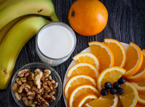 orange slices with glass of milk, a few walnuts, and banana