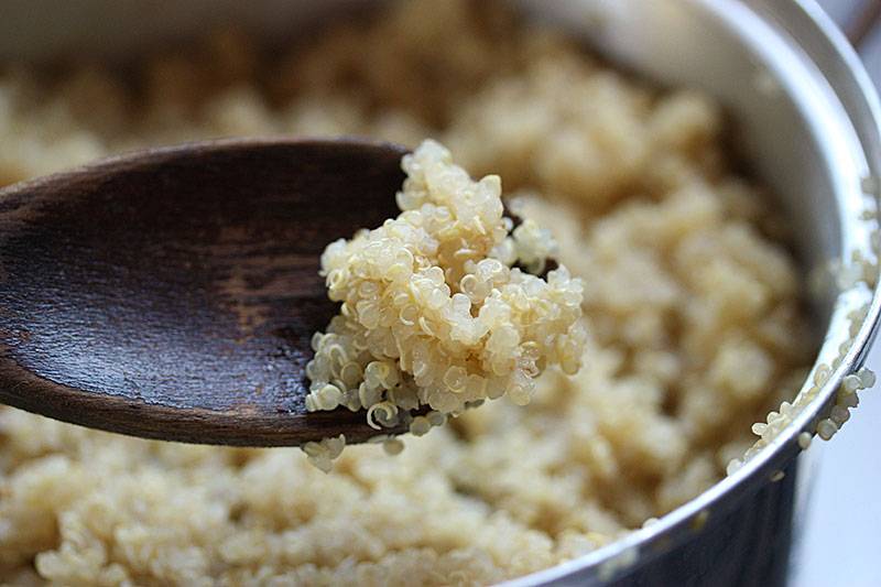 cooked quinoa in pan and a scoop on a wooden spoon 