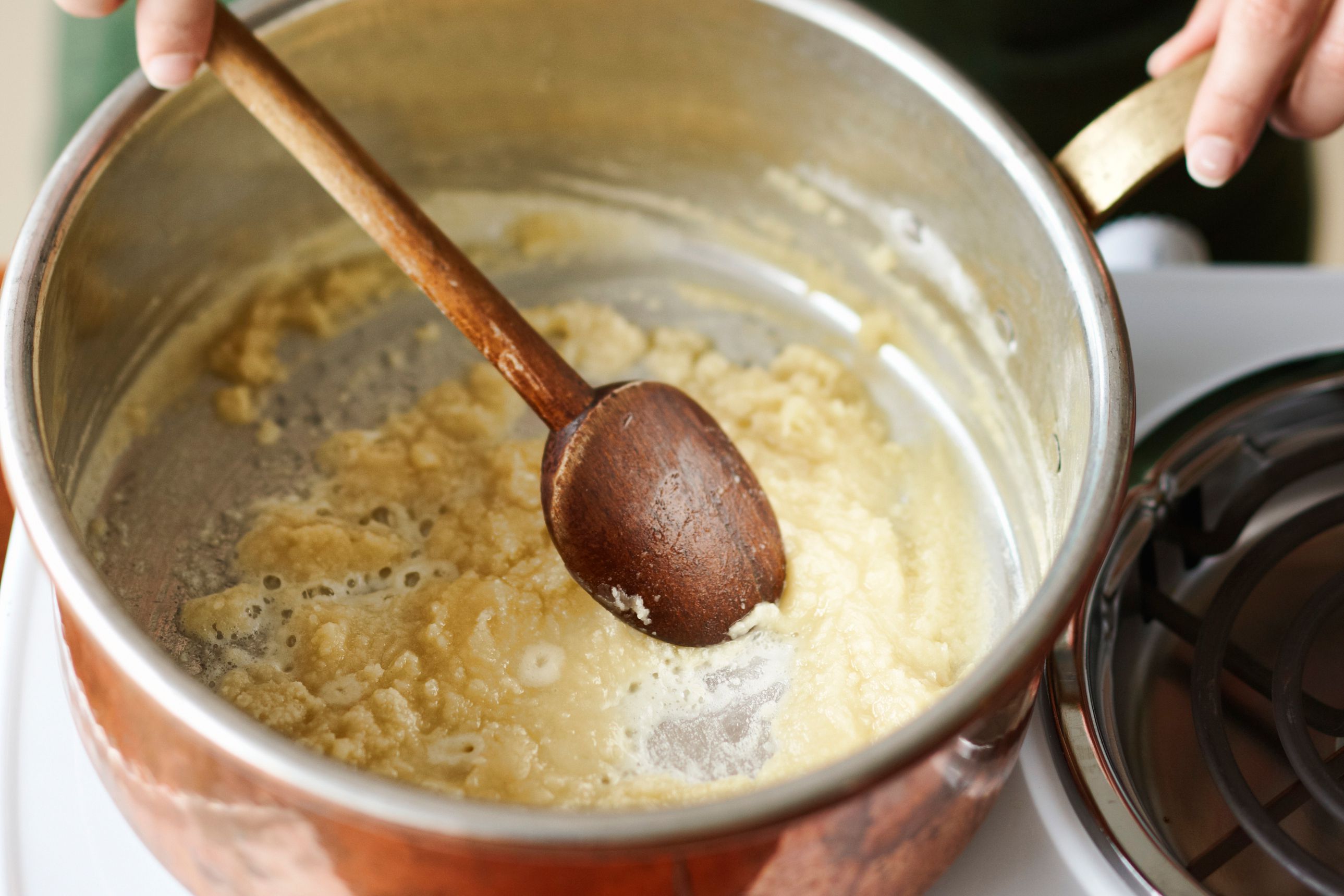 large heavy pan with flour and fat being stirred to make a roux
