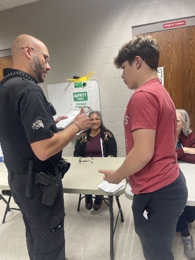 Get Real, Here's the Deal Picture of a student talking and recieving a ticket from a resource officer