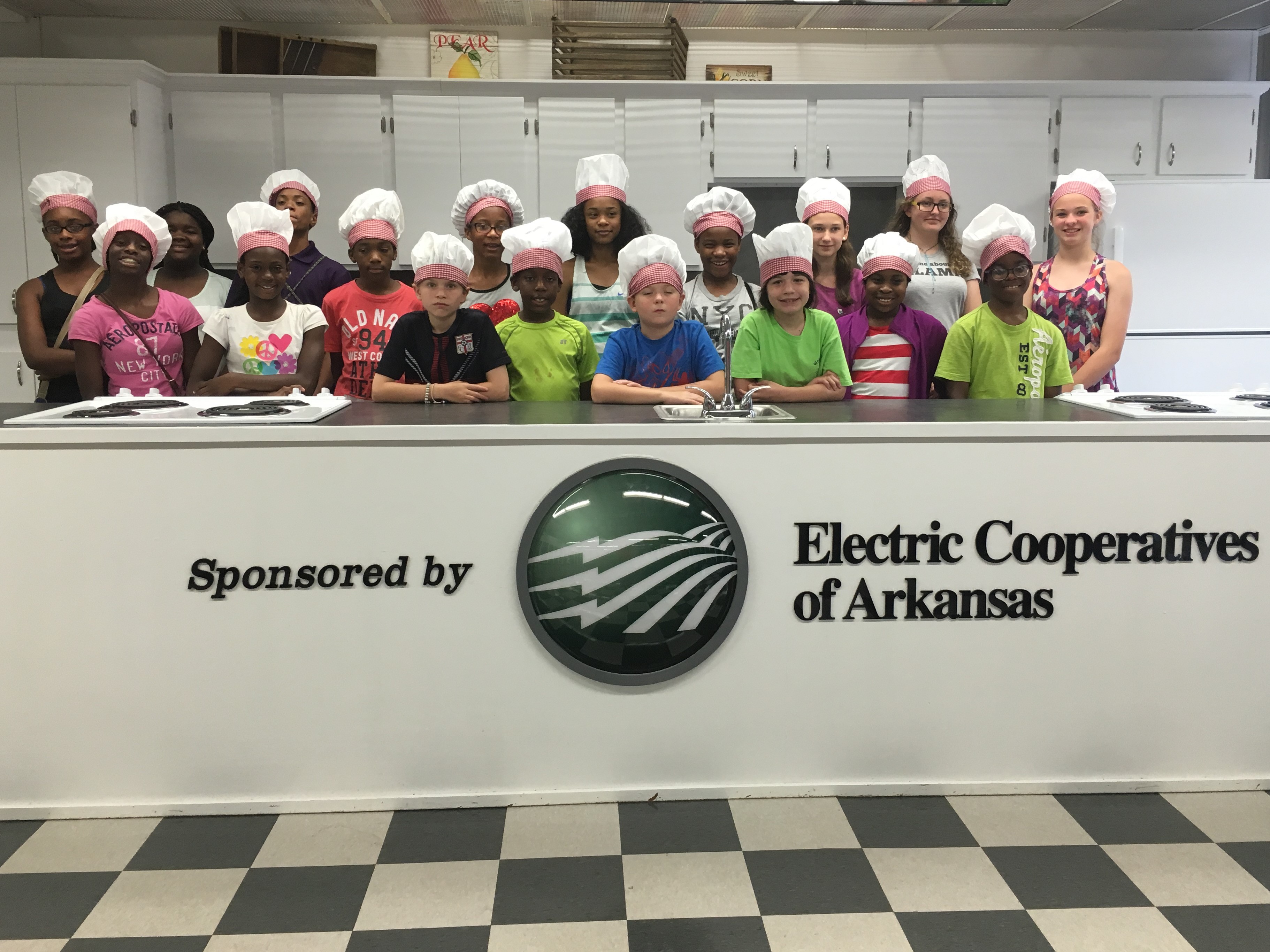 Several 4H members posing for a picture behind a demonstration kitchen during a cooking class.  