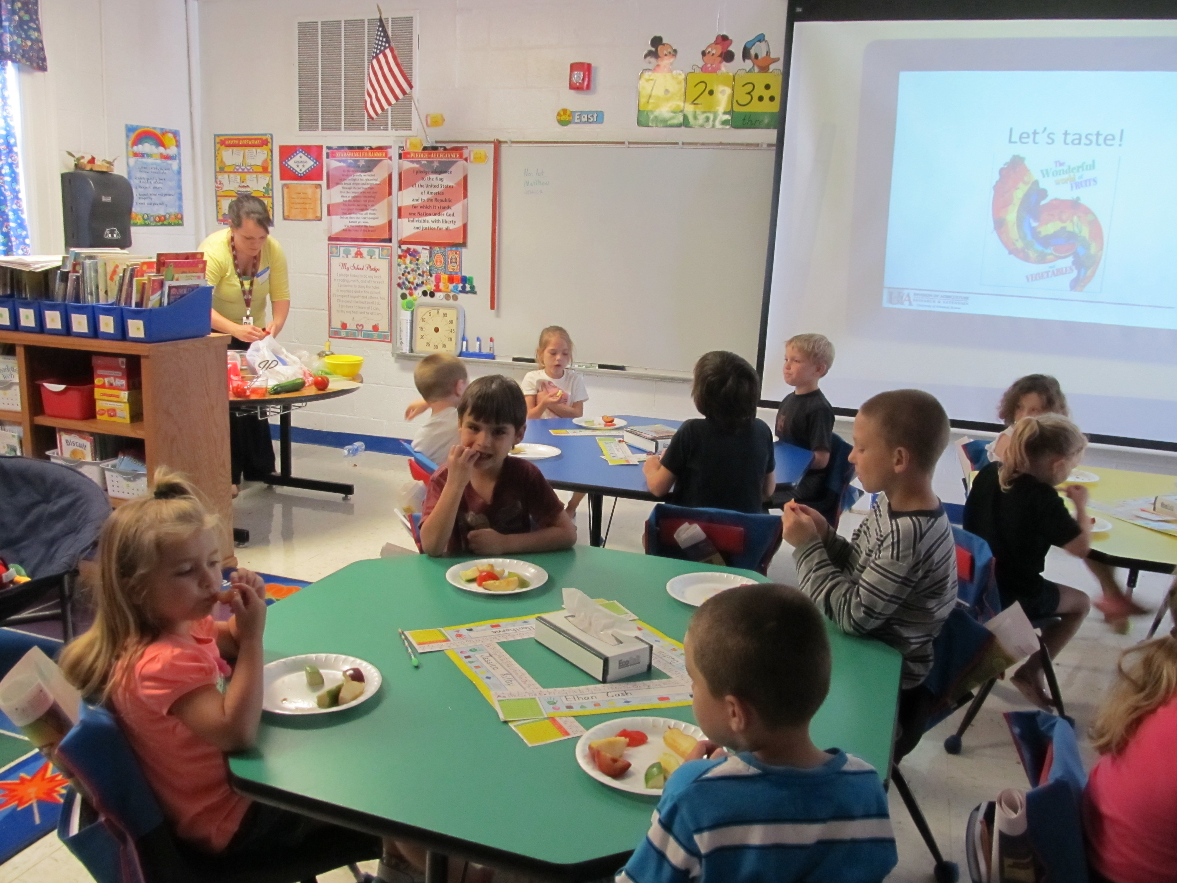 1st graders sample three varieties of apples, zucchini, tomatoes, and two types of plums.