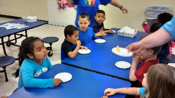 Students at setting at table enjoying a tasting activity as they learn how a cantaloupe looks, feels, tastes, and smells